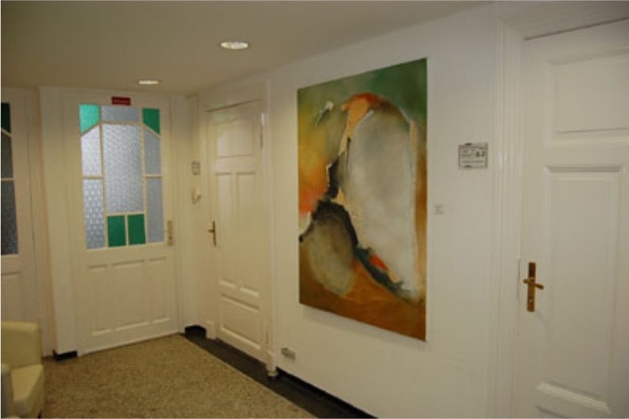 Foto vom Eingangsbereich, man sieht ein großes Gemälde, eine weiße Kassettentür und die nostalgisch verglaste Eingangstür, dazu den denkmalgeschützten Terazzoboden von 1902