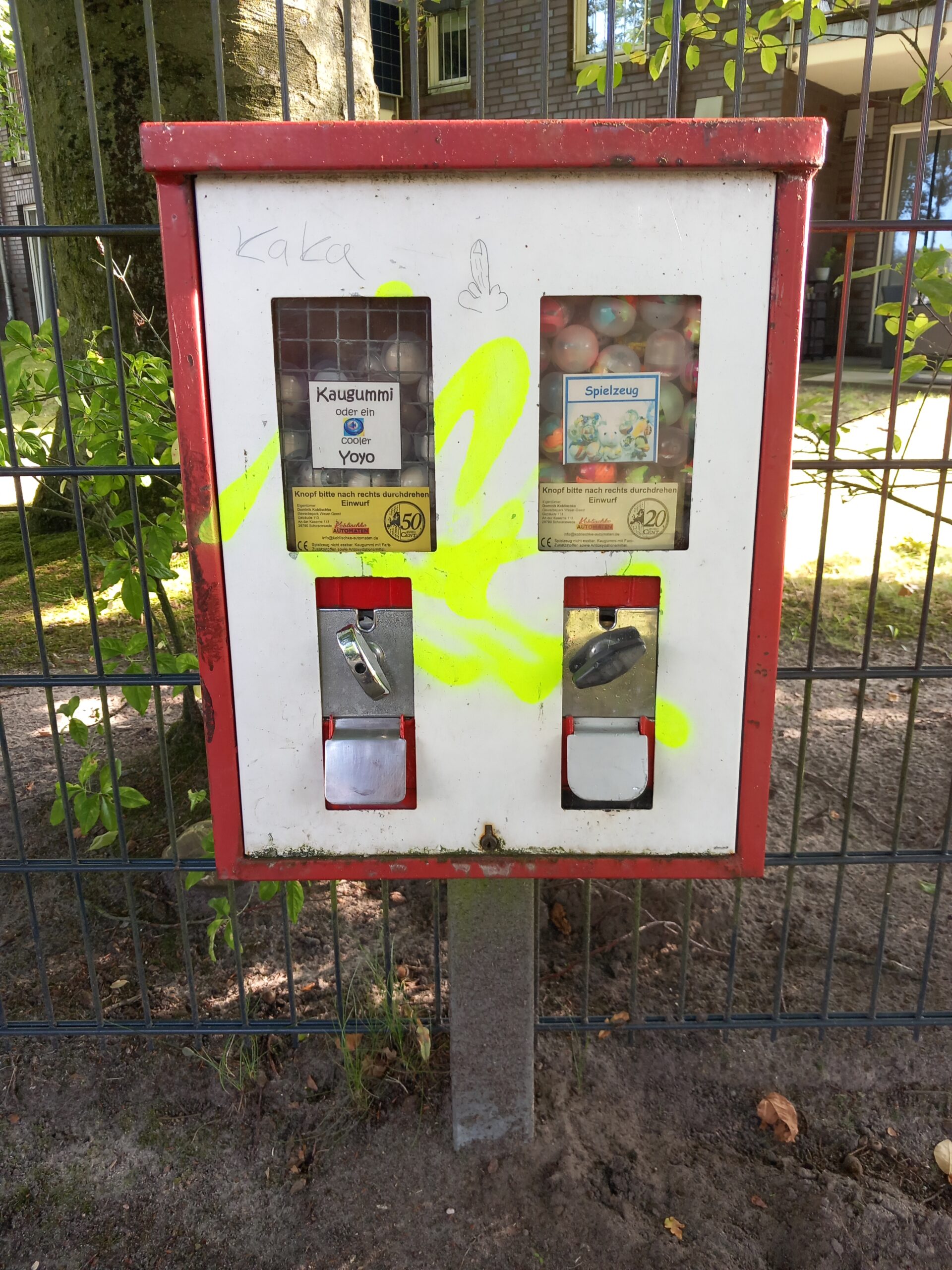 Ein alter Kaugummiautomat am Straßenrand, beschmiert und dreckig